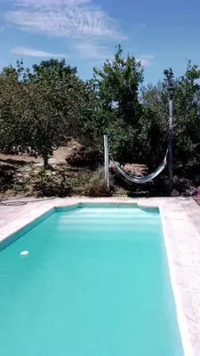 a blue swimming pool with a hammock in the background at Casa Nacha in Cuesta Blanca