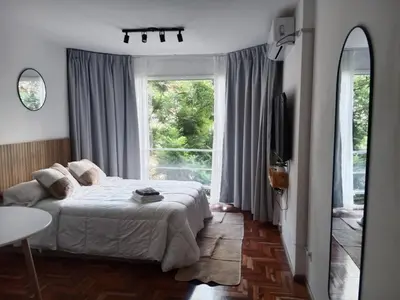a bedroom with a bed and a large window at Encantador departamento en Nueva Córdoba in La Porteña