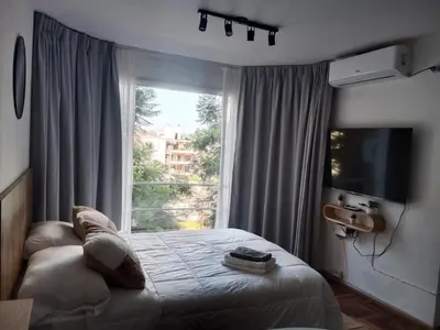 a bedroom with a bed and a large window at Encantador departamento en Nueva Córdoba in La Porteña