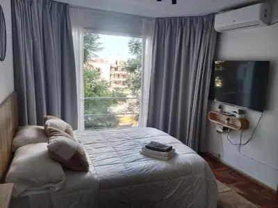 a bedroom with a bed and a large window at Encantador departamento en Nueva Córdoba in La Porteña