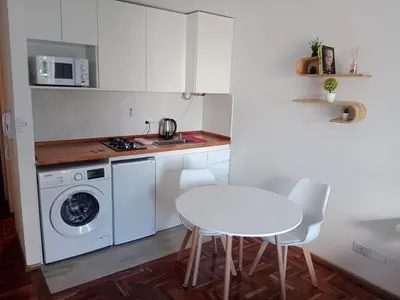 a white kitchen with a table and a washing machine at Encantador departamento en Nueva Córdoba in La Porteña
