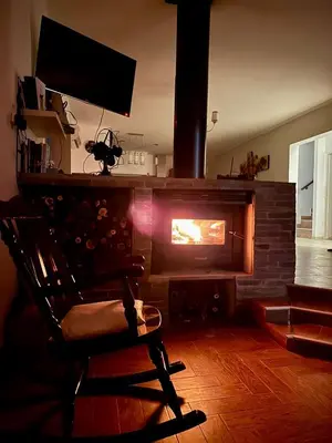 a room with a fireplace with a chair and a television at Casa Valle del Colibrí in Merlo