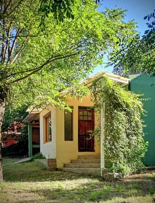 a small yellow house with a red door at Buena tierra in Arroyo de Los Patos
