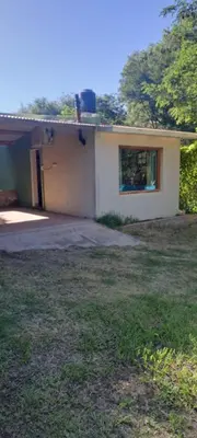 a small white house with a window in a yard at Buena tierra in Arroyo de Los Patos