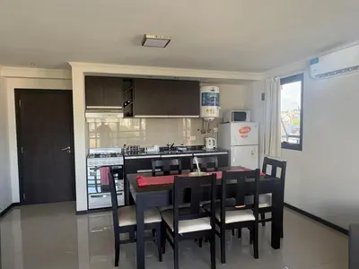 a kitchen with a table and chairs and a kitchen with a refrigerator at Hermoso departamento en el Centro de Carlos Paz in Villa Carlos Paz
