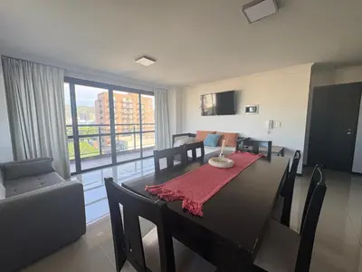 a living room with a dining room table and a room with a couch at Hermoso departamento en el Centro de Carlos Paz in Villa Carlos Paz