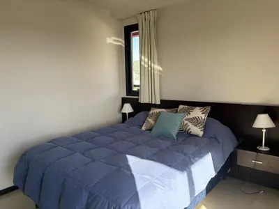 a large blue bed in a bedroom with a window at Hermoso departamento en el Centro de Carlos Paz in Villa Carlos Paz