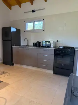 a kitchen with a black refrigerator and a stove at Treffen Cabañas in Villa General Belgrano