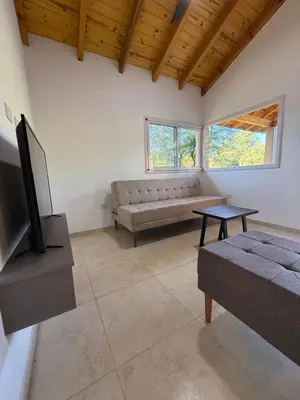 a living room with a couch and a tv at Treffen Cabañas in Villa General Belgrano