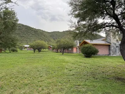 a field of grass with trees and a house at Treffen Cabañas in Villa General Belgrano