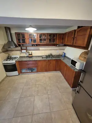 an empty kitchen with wooden cabinets and a refrigerator at Cabaña Dario in Villa Independencia