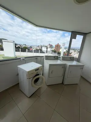 a laundry room with three washing machines and a window at Departamento Carilo in Villa Carlos Paz
