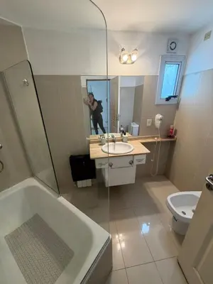 a man taking a picture of a bathroom with a tub and sink at Departamento Carilo in Villa Carlos Paz