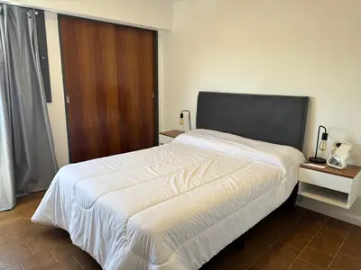 a bedroom with a large white bed and a wooden door at Departamento Nueva Córdoba in Cordoba