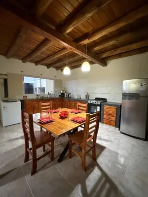 a kitchen with a wooden table with chairs and a refrigerator at Refugio del Alma in Villa Anizacate