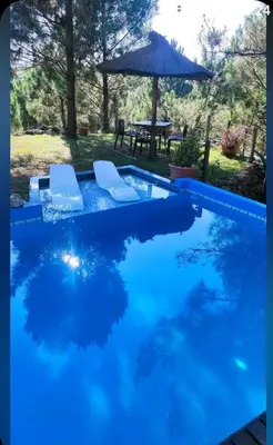 a blue swimming pool with two chairs and an umbrella at Tierra Nuestra in Villa Ciudad de America