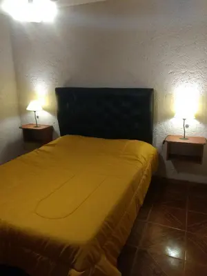 a bedroom with a yellow bed with two lamps at Tierra Nuestra in Villa Ciudad de America