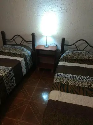 a room with two beds and a lamp on a table at Tierra Nuestra in Villa Ciudad de America