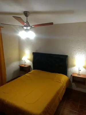 a bedroom with a yellow bed and two lamps at Tierra Nuestra in Villa Ciudad de America