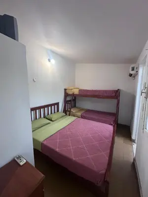 two beds in a small room with purple sheets at Colonia 25 de Mayo in Villa Carlos Paz