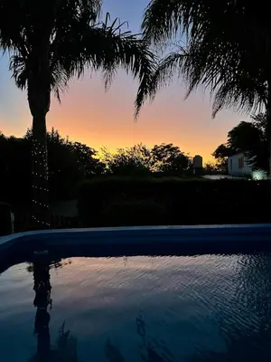 a sunset with a palm tree and a swimming pool at Cabaña Garcia in Santa María