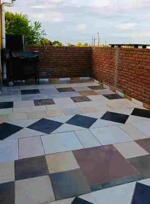 a patio with a checkered floor and a brick wall at Colorido departamento planta alta in Río Tercero