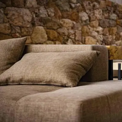 a couch with a pillow in front of a stone wall at Veneto Village Dpto T3 1 K in Villa Parque Siquiman