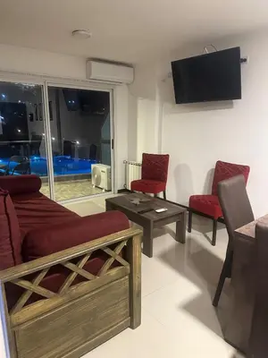 a living room with two red chairs and a flat screen tv at Veneto Village Dpto T3 1 K in Villa Parque Siquiman