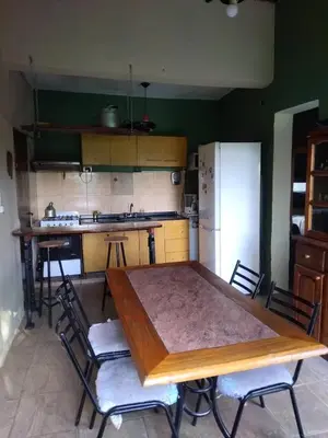 a kitchen with a table and chairs and a refrigerator at Dptos victoria in Mina Clavero