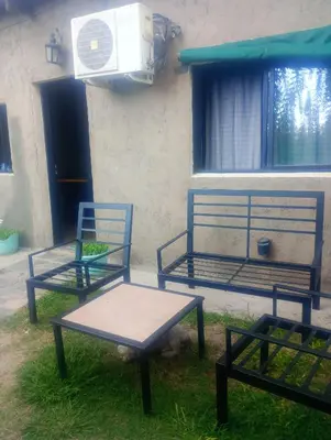 two blue chairs and a bench in front of a building at Dptos victoria in Mina Clavero