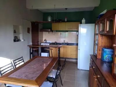 a kitchen with a wooden table and a refrigerator at Dptos victoria in Mina Clavero