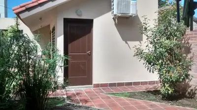 a house with a brown door and a brick sidewalk at Casita del Lago in Villa Carlos Paz
