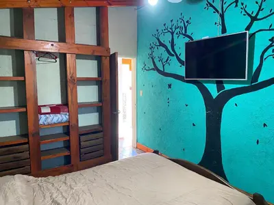 a bedroom with a tree painted on the wall at Departamento El Delfín in Tanti