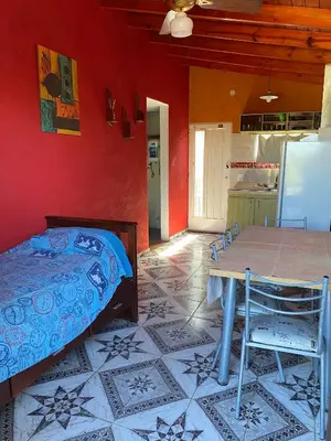 a bedroom with a bed and a table and a kitchen at Departamento El Delfín in Tanti