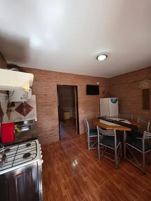 a kitchen with a stove and a table with chairs at Complejo de departamentos 7 Cielos in Villa Carlos Paz