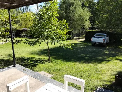 two white benches sitting in a yard with a tree at Casita Santa Elena N3 in Trapiche