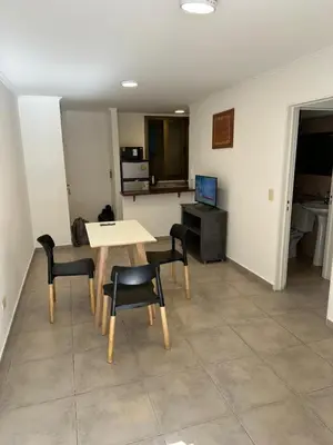 a living room with a table and chairs and a kitchen at Departamento Duarte Quiros 274 in Cordoba