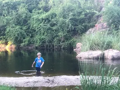 a boy standing in the water in a river at Los árboles in Potrero de Garay