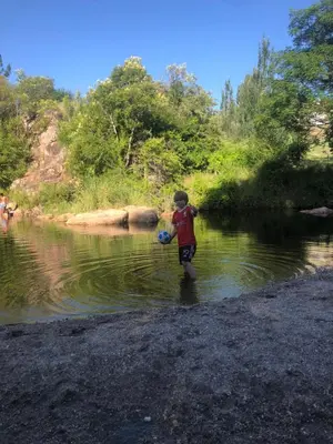 a young boy walking in the water at Los árboles in Potrero de Garay