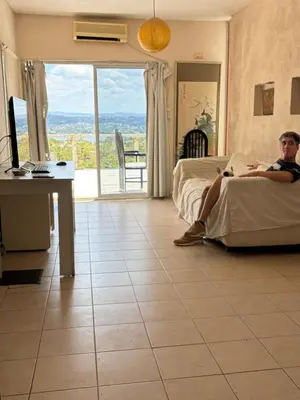 a man sitting on a bed in a hotel room at Depto Vista panoramica in Villa Carlos Paz