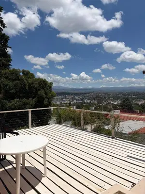 a wooden deck with a table and a view of a city at Depto Vista panoramica in Villa Carlos Paz