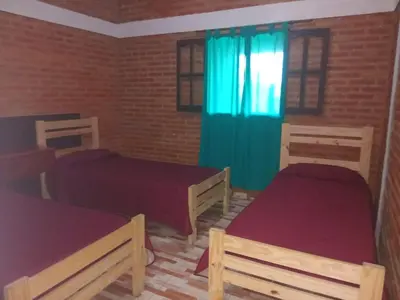a bedroom with two beds and a blue curtain at Casa Camila in Villa Cura Brochero