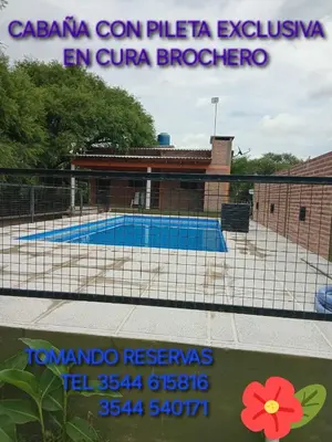 a fence with a swimming pool in front of a building at Casa Camila in Villa Cura Brochero