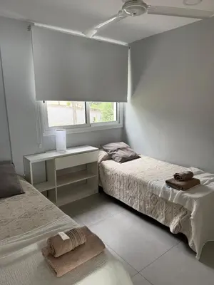 a white bedroom with two beds and a window at Complejo Palo Blanco in Villa Carlos Paz