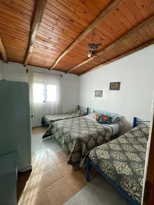 a room with three beds and a wooden ceiling at La Vision, Casa de campo in Villa Quillinzo