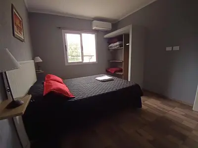 a bedroom with a bed with red pillows and a window at MisdosolesCabañas in Bialet Massé