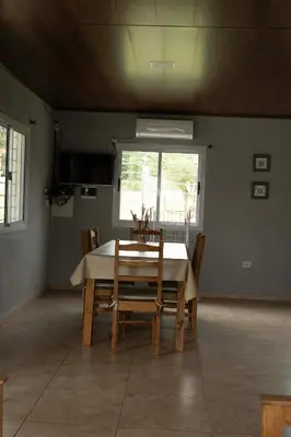 a dining room with a table and chairs and a window at MisdosolesCabañas in Bialet Massé