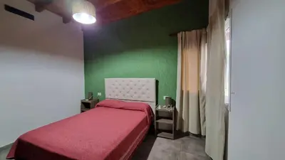 a bedroom with a red bed with a green wall at Cabañas La casita de las sierras in Barrio Parque El Corcovado