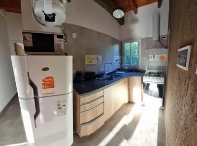 a kitchen with a white refrigerator and a stove at Cabañas La casita de las sierras in Barrio Parque El Corcovado