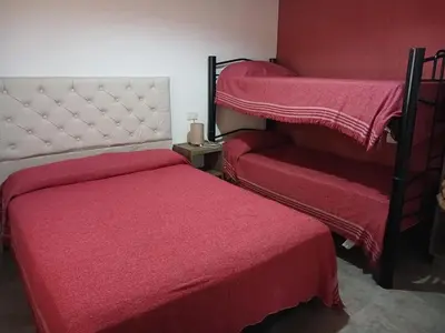 a bedroom with two beds with red sheets and a headboard at Cabañas La casita de las sierras in Barrio Parque El Corcovado